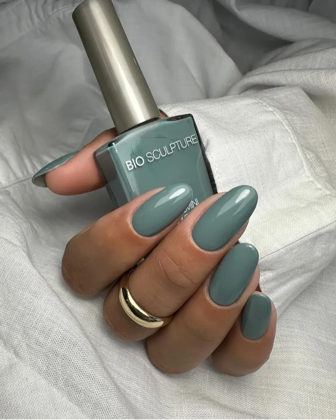 Main tenant un flacon Bio Sculpture, ongles vert de gris