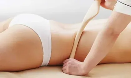 Massage HinokiBô avec un bâton en bois sur le ventre