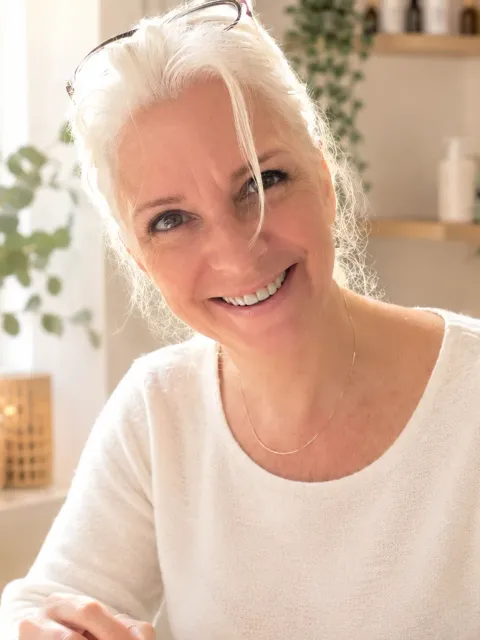 Portrait de Nathalie, esthéticienne à domicile, souriante, en pull crème